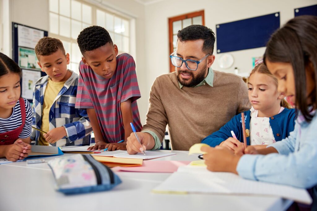 Children are gathered around a teacher in a classroom.